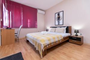 a bedroom with a large bed and red curtains at Chic Urban Retreat: Modern 2-Bedroom Gem for Your City Escape in Plovdiv