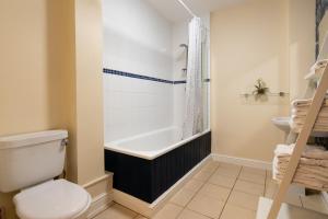 a bathroom with a tub and a toilet and a sink at Aryas Apartments Oxford - Headington in Oxford