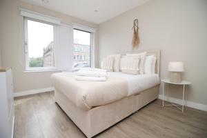 a white bedroom with a large bed with white pillows at 2 BR and Free parking in Cardiff