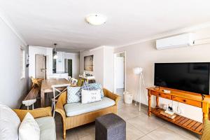 a living room with a couch and a tv at Sunny Beach Front Apartment in Ballito