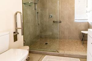 a bathroom with a shower with a glass door at Sunny Beach Front Apartment in Ballito +17 photos