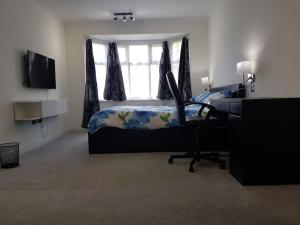 a bedroom with a bed and a desk and a window at Contemporary ground flr maisonette- Entire place in Northwood