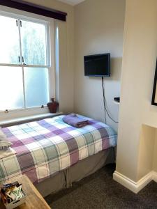 ein Schlafzimmer mit einem Bett und einem TV an der Wand in der Unterkunft Single Room - Bed for the night - Close to Beach in St. Leonards