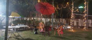 a patio with tables and a red umbrella and lights at The Beatrix Resort & Wellness in Lucknow