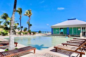 una piscina con bancos y palmeras y un edificio en Preciosas vista al mar, a 10 min. del aeropuerto -Sol2401- en Cancún