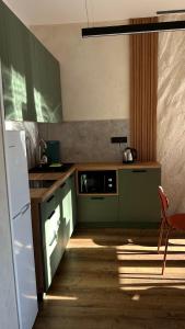 La cuisine est équipée de placards verts et d'un réfrigérateur blanc. dans l'établissement Котедж Gudz, à Yaremtche