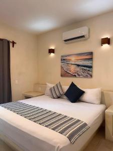 a bedroom with a white bed with a painting on the wall at Hotel Aldea Sol in Zihuatanejo