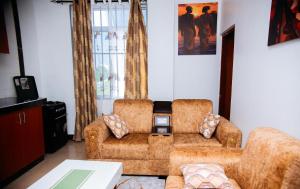 ein Wohnzimmer mit 2 Stühlen und einem Sofa in der Unterkunft DOMINGO VILLA in Daressalam