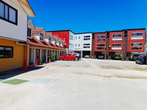 una calle de la ciudad con edificios y un coche rojo estacionado en Hostal Esesur, en Puerto Montt
