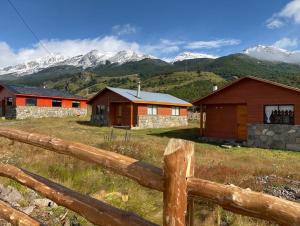 ein Holzzaun auf einem Feld mit Häusern und Bergen in der Unterkunft Cabañas El Diamante in Villa Maniguales