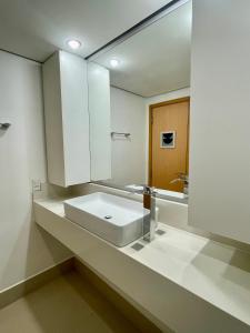 uma casa de banho com um lavatório branco e um espelho. em Flat no hotel Q. Paulista nos Jardins, com sacada! em São Paulo