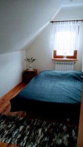 a bedroom with a blue bed and a window at Enklawa Spokoju in Słójka Borowszczyzna