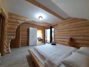 um quarto com uma cama branca num quarto com paredes de madeira em CABANA BELVEDERE em Borşa
