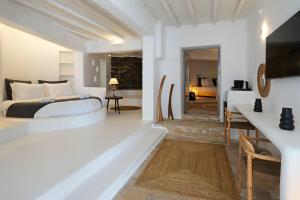 White Stone Mykonos في أغيوس يوانيس ميكونوس: غرفة نوم مع سرير وغرفة معيشة