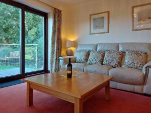 a living room with a couch and a table with a bottle of wine at Caer Dderwen Oak Field family home in Dolgellau in Dolgellau