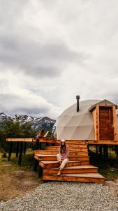 a person sitting on a bench in front of a tent at Estancia Patagonia El Calafate - Pristine Luxury Camps in El Calafate