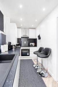 uma cozinha com armários a preto e branco e cadeiras pretas em Modern 1 Bed Studio Flat Leeds em Headingley