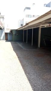 a building with a long shadow on the ground at Apto 03 - 1 quarto com 2 camas solteiro e garagem, possui ventilador de teto in Cascavel