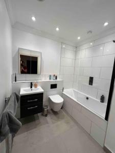 uma casa de banho branca com uma banheira, um WC e um lavatório. em Entire 1 bed apartment-Convenient and peaceful amenable stay em Londres