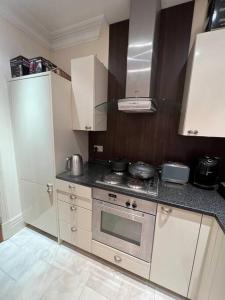 a kitchen with white cabinets and a stove top oven at Entire 1 bed apartment-Convenient and peaceful amenable stay in London