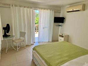 - une chambre avec un lit, une table et une télévision dans l'établissement Pousada Mansão Triplex Jolly, à Búzios