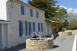 ein Gebäude mit blauen Fenstern und einem Brunnen davor in der Unterkunft Gîte les 2 Fontaines in Marans