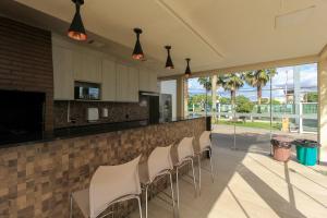 a kitchen with a bar with white chairs at Ap Cloe com piscina próximo ao Aeroporto in Porto Alegre