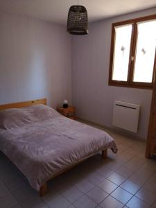 ein Schlafzimmer mit einem Bett und zwei Fenstern in der Unterkunft maison le Rossignol in Châtillon-en-Diois