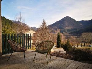 two chairs sitting on a wooden deck with mountains in the background at maison le Rossignol in Châtillon-en-Diois