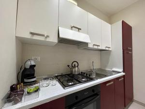 uma cozinha com armários brancos e um forno com placa de fogão em A casa di Alli em Palermo