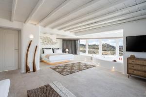 White Stone Mykonos في أغيوس يوانيس ميكونوس: غرفة نوم بسرير وحوض استحمام وتلفزيون