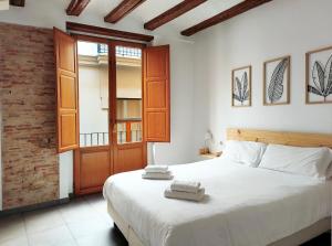a bedroom with a large white bed and a wooden door at Flats Friends Tetuan in Valencia