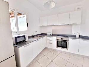 a white kitchen with a sink and a microwave at Casa Tabaiba in Tías