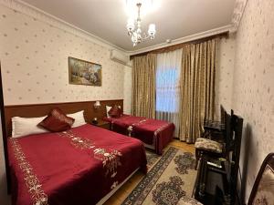 a hotel room with two beds and a chandelier at Sarbon Hotel Tashkent in Tashkent