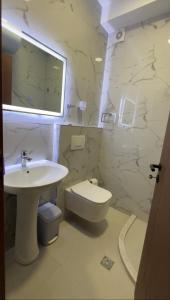 Baño blanco con lavabo y aseo en Bujtina ALDOR en Berat