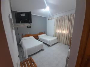 Habitación pequeña con 2 camas y TV. en Hotel Restaurante Peñarroya, en Argamasilla de Alba
