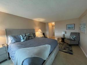 a bedroom with a large bed and a chair at Bikinis and Martinis at Dolphin Run-Oceanfront-Pool! in Virginia Beach