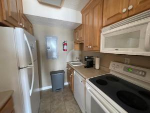 a kitchen with a white refrigerator and a stove top oven at Playing Hooky at Dolphin Run-Oceanfront Condo-Pool in Virginia Beach