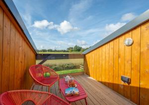 una terraza con 2 sillas rojas y una mesa en No.2 Long Barn, en Wangford