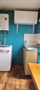 una pequeña cocina con fregadero y nevera. en Cabaña Puerto Williams en Puerto Williams