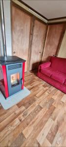 a living room with a red couch and a fireplace at Cabaña Puerto Williams in Puerto Williams
