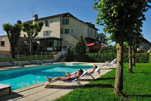 two people laying in chairs next to a swimming pool at La Route d'Argent in Bozouls