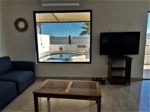 uma sala de estar com uma televisão, um sofá e uma mesa em Casa Loma Bella 1 con Alberca Privada Vista Increible em San Carlos