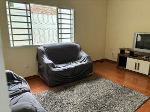uma sala de estar com uma cadeira de couro e uma televisão em Hostel do Mineiro em São José dos Campos