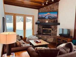 a living room with couches and a fireplace with a tv at 100 Steps Away Ski in Ski Out Condo in Big Sky