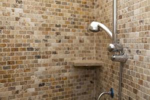 a shower in a brick wall with a hose at Guest house Acuario in Torre Grande