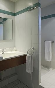 a bathroom with a sink and a shower with a mirror at La Route d'Argent in Bozouls