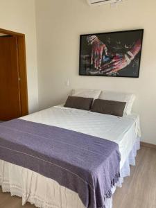 Un dormitorio con una cama con una manta morada. en Casa de Campo Ninho Verde 2 en Pardinho