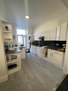 a large kitchen with white cabinets and a window at Tynwald Apartments in Douglas