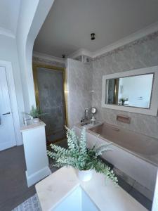 baño con bañera, lavamanos y planta en Tynwald Apartments, en Douglas